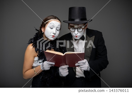 Mime couple intently reading a book together Mime couple intently reading a book together 143376011