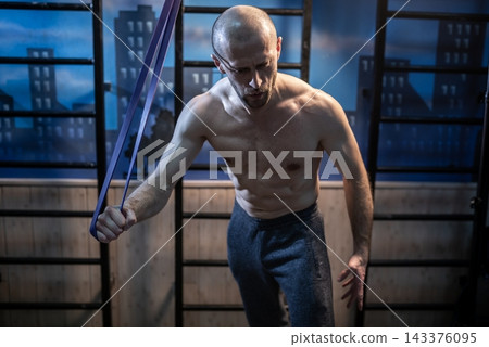 Man stretching with an elastic resistance loop at a sports facility Man stretching with an elastic resistance loop at a sports facility 143376095