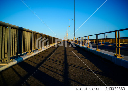 A long bridge stretching across the blue sky where the moon is visible. A long bridge stretching across the blue sky where the moon is visible. 143376883