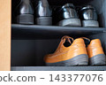 Leather shoes lined up in a shoe rack. Stored on shelves. 143377076