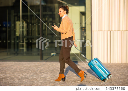 Woman Walking with Suitcase at Modern Transport Hub Woman Walking with Suitcase at Modern Transport Hub 143377368