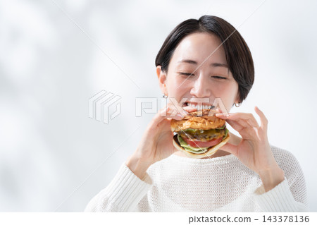 A smiling woman eating a delicious hamburger A smiling woman eating a delicious hamburger 143378136