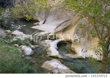Clear Rio Vero flowing between white polished limestone shapes under poplar branches Clear Rio Vero flowing between white polished limestone shapes under poplar branches 143378723