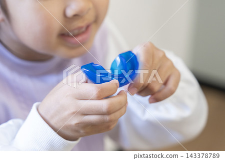 A 6-year-old girl's hand holding an orthodontic mouthpiece. A 6-year-old girl's hand holding an orthodontic mouthpiece. 143378789