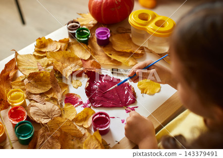 Child's hands creating autumn leaf artwork with paint and brush. Developing creativity and fine motor skills with fall diy project Child's hands creating autumn leaf artwork with paint and brush. Developing creativity and fine motor skills with fall diy project 143379491