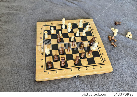Chess game in progress on a wooden board Chess game in progress on a wooden board 143379983