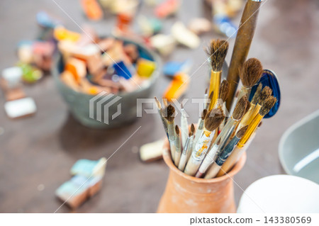 Paintbrushes for glazing and decorating ceramics stand on pottery workshop table. Ceramic tools represent craftsmanship and handmade pottery creation Paintbrushes for glazing and decorating ceramics stand on pottery workshop table. Ceramic tools represent craftsmanship and handmade pottery creation 143380569
