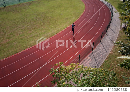 Woman running on stadium track, aerial view Woman running on stadium track, aerial view 143380888