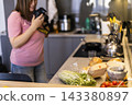 Woman photographing ingredients on kitchen counter with shallow depth 143380897