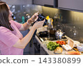 Woman photographing food ingredients in kitchen with camera 143380899