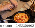Cooking scrambled eggs with tomatoes in a frying pan while cracking 143380902