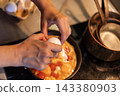 Cracking egg into pan with tomatoes and eggs 143380903