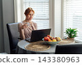 Middle aged woman using laptop drink morning coffee at kitchen table. Female entrepreneur working remotely, has online e-learning course video conference call at home. freelance concept. . Online Job. 143380963