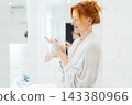 Relaxed middle aged woman Applying Hand Cream in bathroom during morning routine, Dry Skin Remedy. Skin hydrating. Cosmetic spa procedures. Beauty self-care at home. Home Beauty treatment routine 143380966