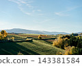 Autumn fields stretch toward distant mountains under clear sky. Concept of agriculture, landscape, seasonality, nature, countryside and rural scenery 143381584