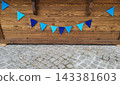 Blue triangular flags are hanging on the wooden background of the wall 143381603