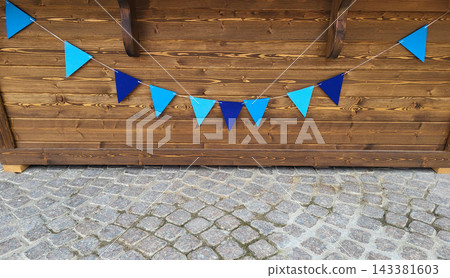 Blue triangular flags are hanging on the wooden background of the wall Blue triangular flags are hanging on the wooden background of the wall 143381603
