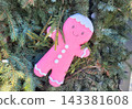 On the stores facade, a pink gingerbread man is hanging from the branches of a Christmas green tree. 143381608