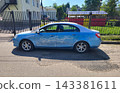 On a summer day, a car is standing in the yard. A white dragon is painted on the side of the blue car. 143381611