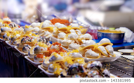Traditional Thai crispy pancakes Khanom Buang displayed at a vibrant Asian night market 143381995
