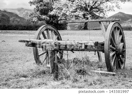 Black and white vintage wooden cart in a scenic mountain landscape Black and white vintage wooden cart in a scenic mountain landscape 143381997