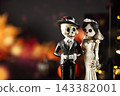 Skeleton bride and groom figurines beside glowing haunted house, pumpkins and smoke. Gothic Halloween wedding decorations on dark background with ample copy space. Halloween holiday card. 143382001