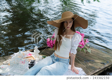 Relaxed summer afternoon by lake. Peaceful scene of lady with pink flower on dockside. Tranquil moment featuring woman with lotus flower near calm lake in vintage style Relaxed summer afternoon by lake. Peaceful scene of lady with pink flower on dockside. Tranquil moment featuring woman with lotus flower near calm lake in vintage style 143382150