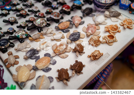 Carved stone and abalone shell turtle souvenirs on market table 143382467