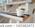 White ceramic coffee cup on weathered wooden stair step outdoors 143382473