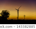Wind turbine silhouette against yellow sunset sky 143382885
