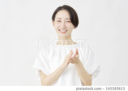 Middle-aged woman applauding against a white background. Middle-aged woman applauding against a white background. 143385613