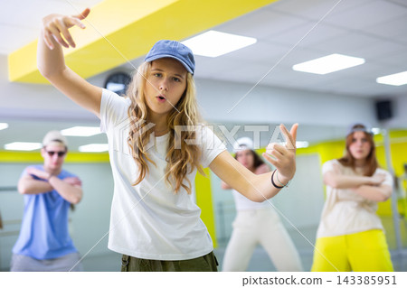 Teenage girl in cap training breakdance Toprock moves in dance hall Teenage girl in cap training breakdance Toprock moves in dance hall 143385951