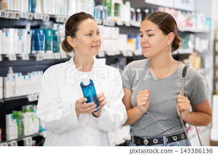 Female buyer consults the pharmacist which lotion or ointment to buy at pharmacy Female buyer consults the pharmacist which lotion or ointment to buy at pharmacy 143386136