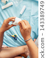person holding a medical bandage roll while preparing first aid supplies at home with close up view of hands and medical materials on blue fabric background. concept of healthcare, rehabilitation 143389749