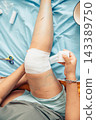 person applying a bandage to an injured knee during first aid at home with close up view of wound care and recovery process. concept of healthcare, rehabilitation, family medicine, pediatric care 143389750