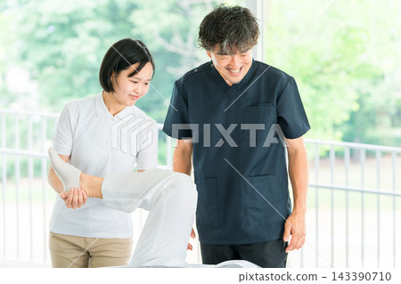 一名年輕的女員工正在接受按摩和物理治療培訓,一名男性物理治療師正在指導她。 一名年輕的女員工正在接受按摩和物理治療培訓,一名男性物理治療師正在指導她。 143390710