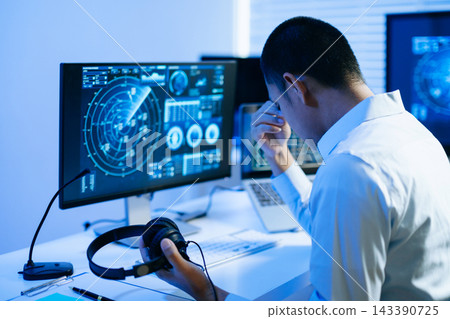 Exhausted air traffic controller holding his face in hands from stress and fatigue while working in a dark Exhausted air traffic controller holding his face in hands from stress and fatigue while working in a dark 143390725
