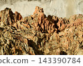 A geological feature with a rugged surface and distinct details, composed of alternating layers of reddish-brown and beige rock. 143390784
