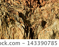Texture or background of a geological feature with a rugged surface and distinct details, composed of alternating layers of reddish-brown and beige rock. 143390785