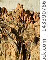 Texture or background of a geological feature with a rugged surface and distinct details, composed of alternating layers of reddish-brown and beige rock. 143390786