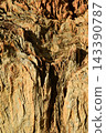 Texture or background of a geological feature with a rugged surface and distinct details, composed of alternating layers of reddish-brown and beige rock. 143390787