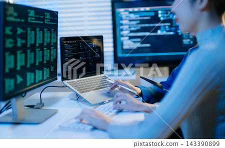 Two female programmers collaborate late in a modern tech office, analyzing computer code on screens to optimize software development Two female programmers collaborate late in a modern tech office, analyzing computer code on screens to optimize software development 143390899