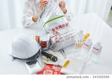 A woman preparing disaster preparedness supplies. A woman preparing disaster preparedness supplies. 143392040
