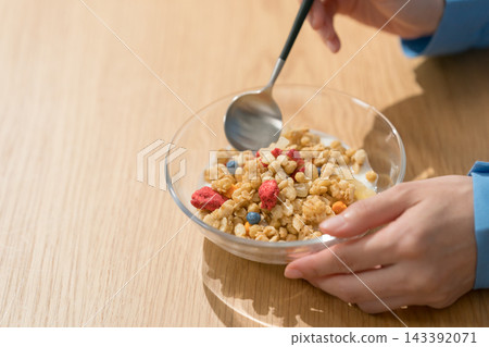 一位女士用湯匙舀格蘭諾拉麥片。 一位女士用湯匙舀格蘭諾拉麥片。 143392071