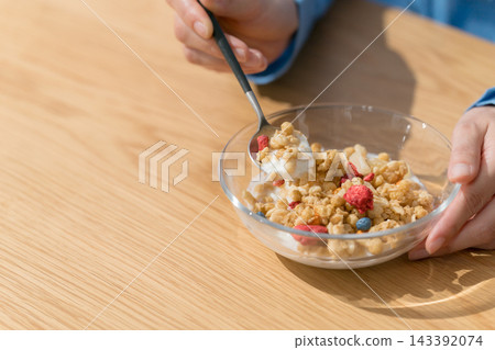 一位女士用湯匙舀格蘭諾拉麥片。 一位女士用湯匙舀格蘭諾拉麥片。 143392074