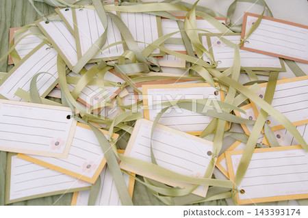 A top-down view of neatly stacked and untied gift wrapping materials, including papers and ribbons, in a casual and organized manner. The scene is set indoors, possibly for event planning. A top-down view of neatly stacked and untied gift wrapping materials, including papers and ribbons, in a casual and organized manner. The scene is set indoors, possibly for event planning. 143393174