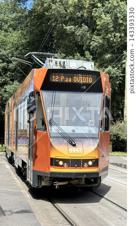橙色電車穿梭在米蘭的街道上。 143393330