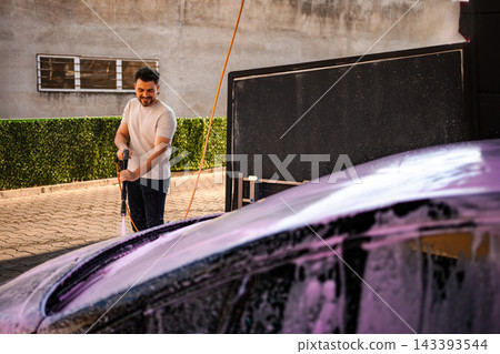 Young adult man washing car with foam and high-pressure water Young adult man washing car with foam and high-pressure water 143393544