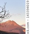 Mount Yufu and tree branches bathed in the red glow of the setting sun 143394019