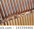 Metal tubes made of copper arranged in a row, featuring varying colors and textures 143394466